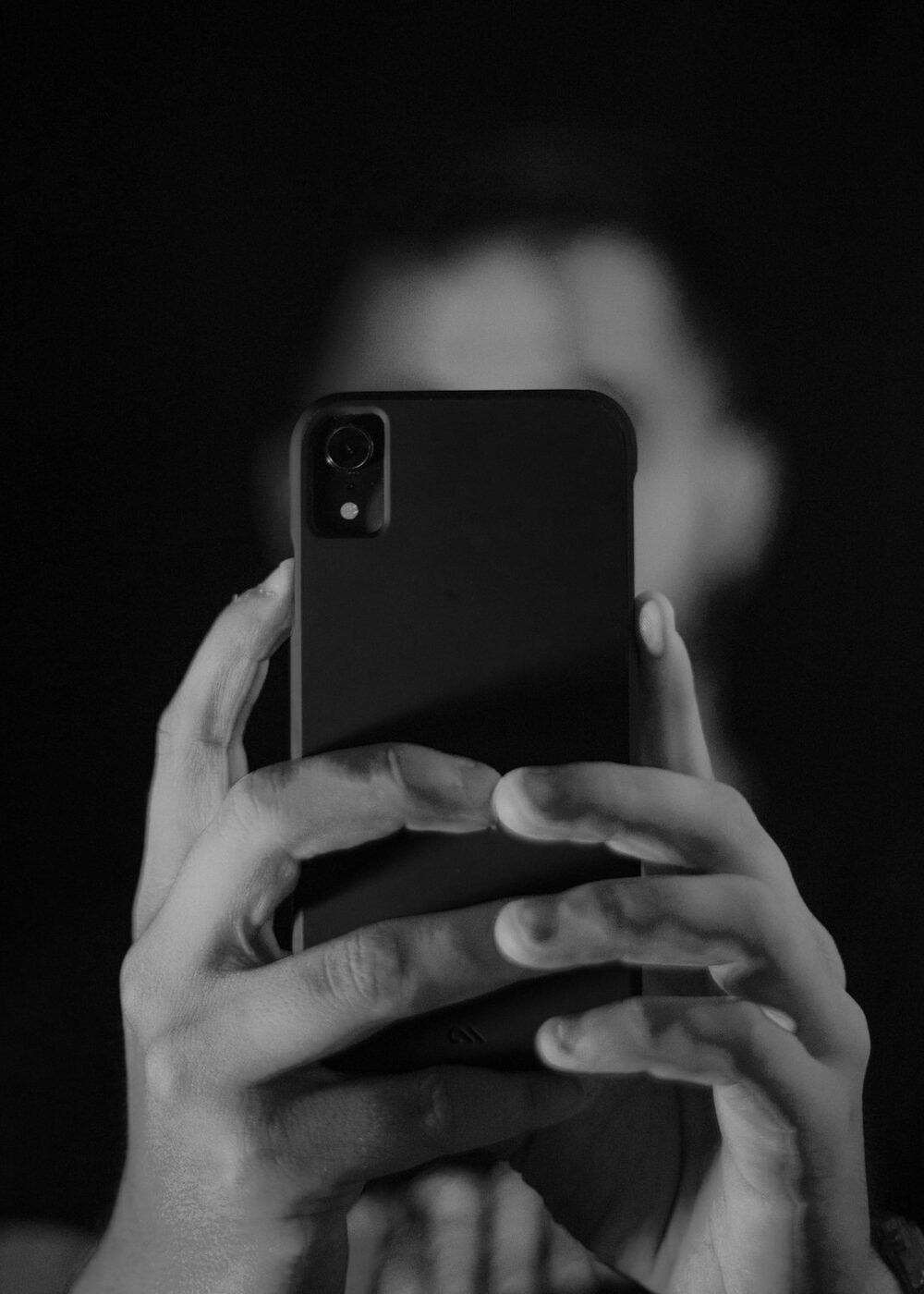 A person's face hidden behind a phone screen